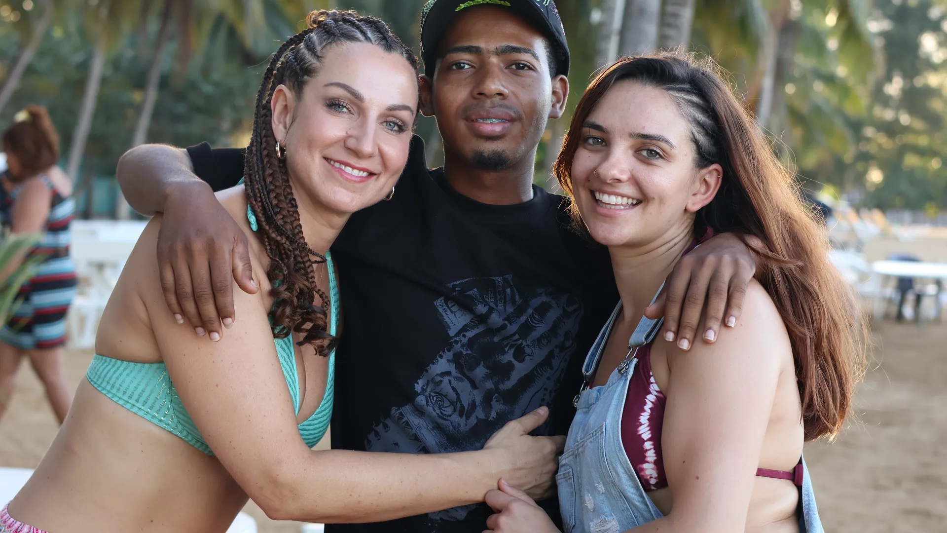 Dos viajeras y su guía abrazados en la playa