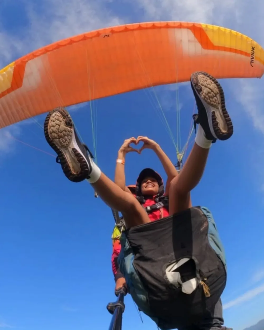 Viajera formando un corazón con las manos durante un vuelo en parapente